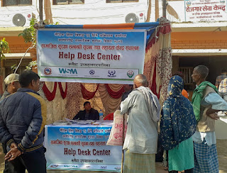 Various people, inlcuding elderly, at a help desk receiving assistance to enroll in social security schemes 